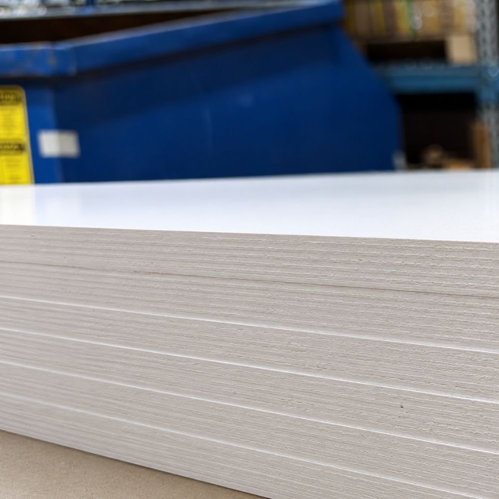 Close-up of a sheet of white cardboard with a blue container in the background.