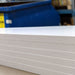 Close-up of a sheet of white cardboard with a blue container in the background.