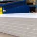 Close-up of a sheet of white cardboard with a blue container in the background.
